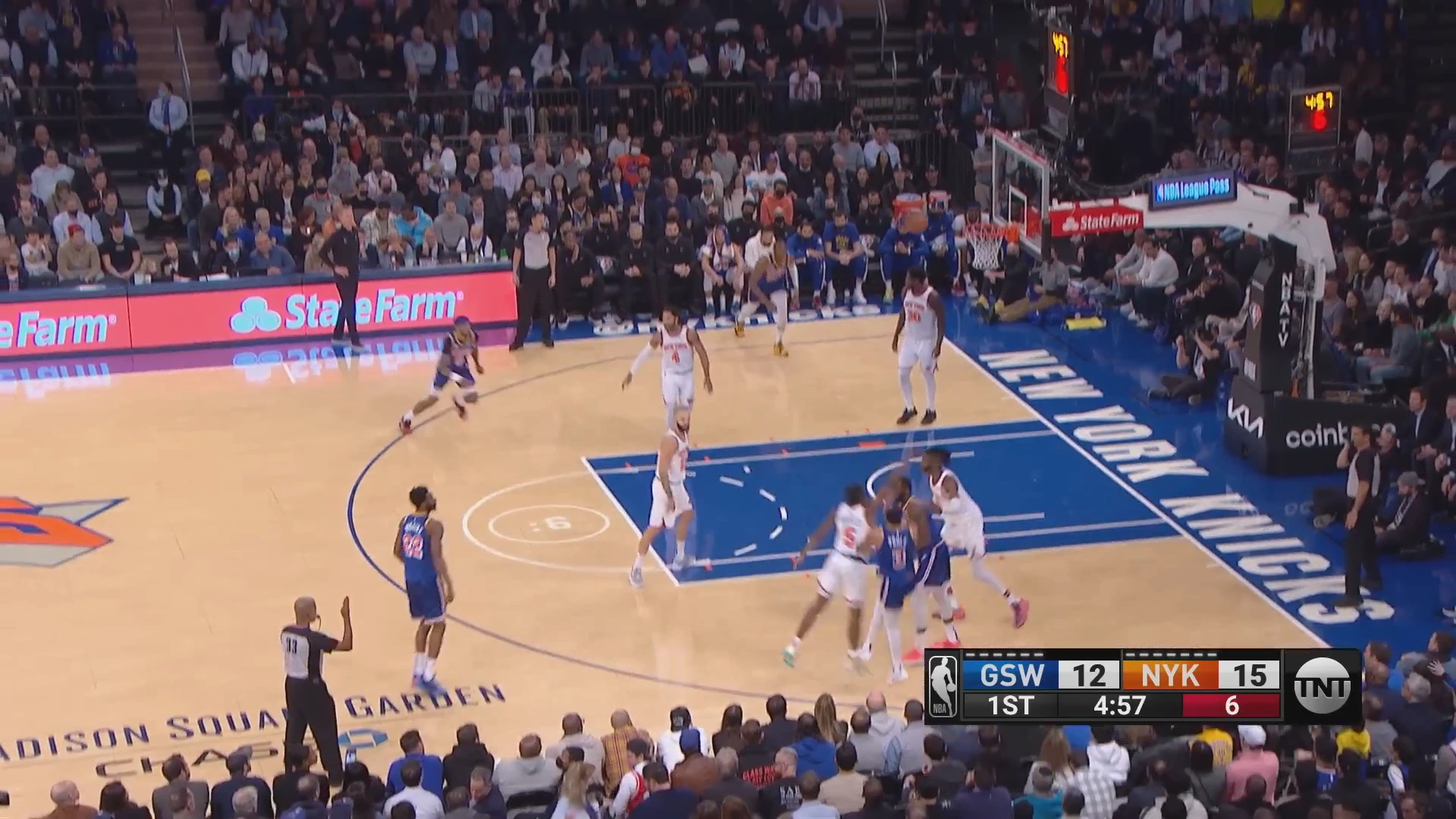 A broadcast frame of the Warriors at the Knicks, the ball in the air in front of the crowd